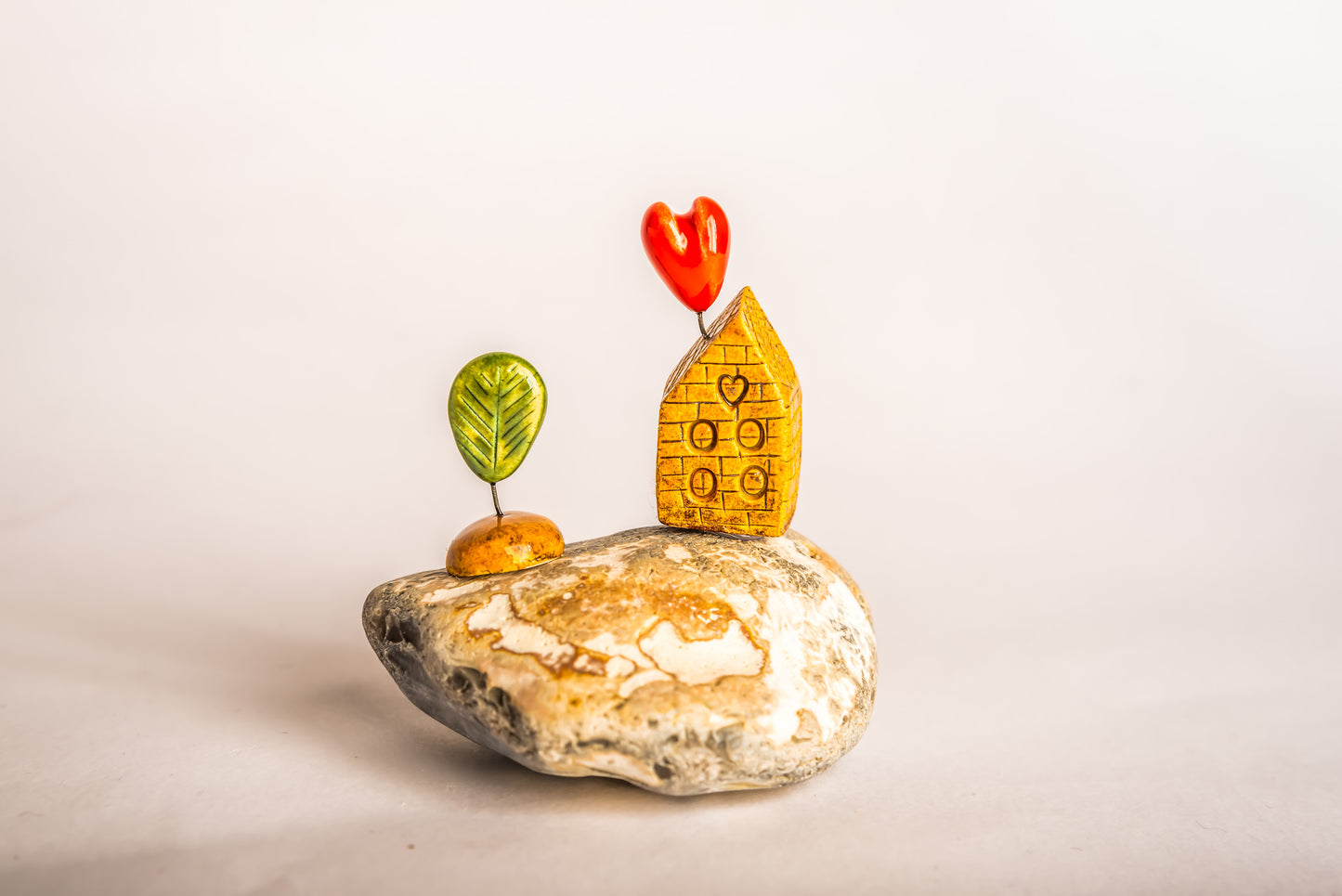 Hand-built brown brick ceramic house on a rock, with a love heart and a tree