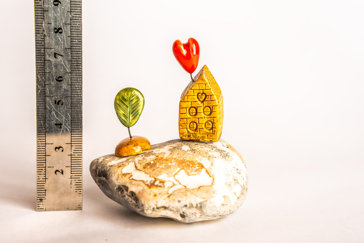 Hand-built brown brick ceramic house on a rock, with a love heart and a tree