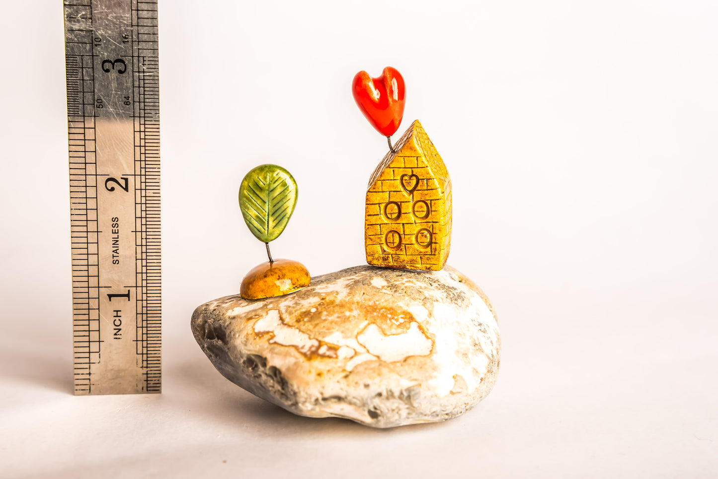 Hand-built brown brick ceramic house on a rock, with a love heart and a tree