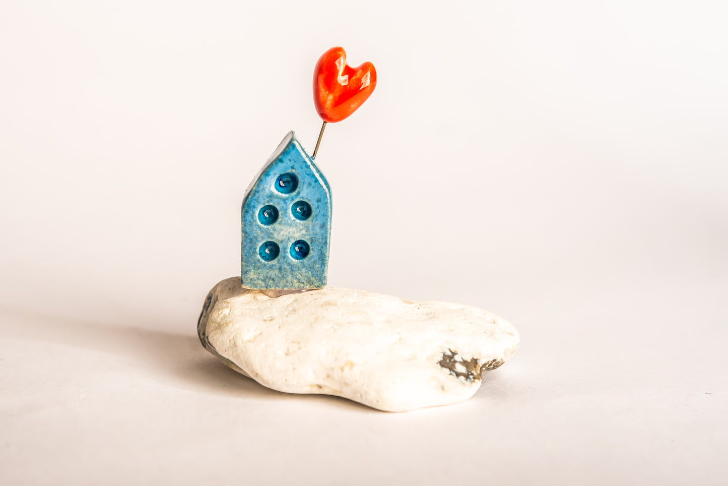 Hand-built blue ceramic house on a rock, with a love heart