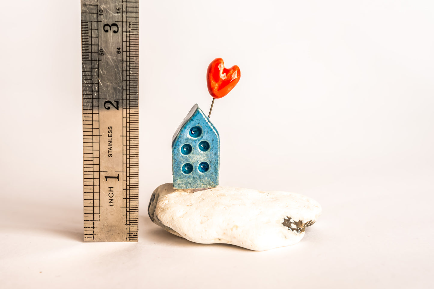 Hand-built blue ceramic house on a rock, with a love heart