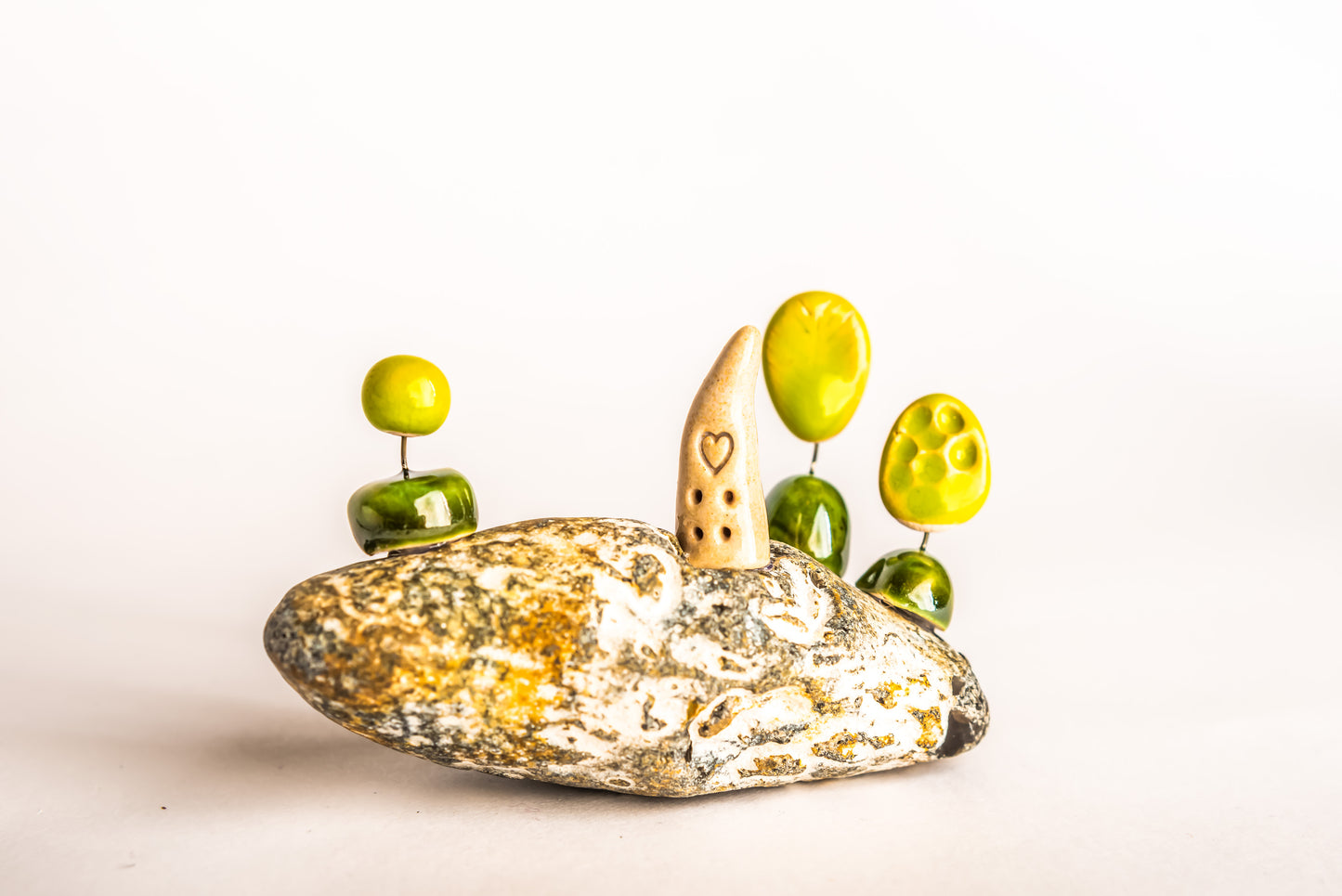 Hand-built fantasy ceramic house on a rock, with three trees