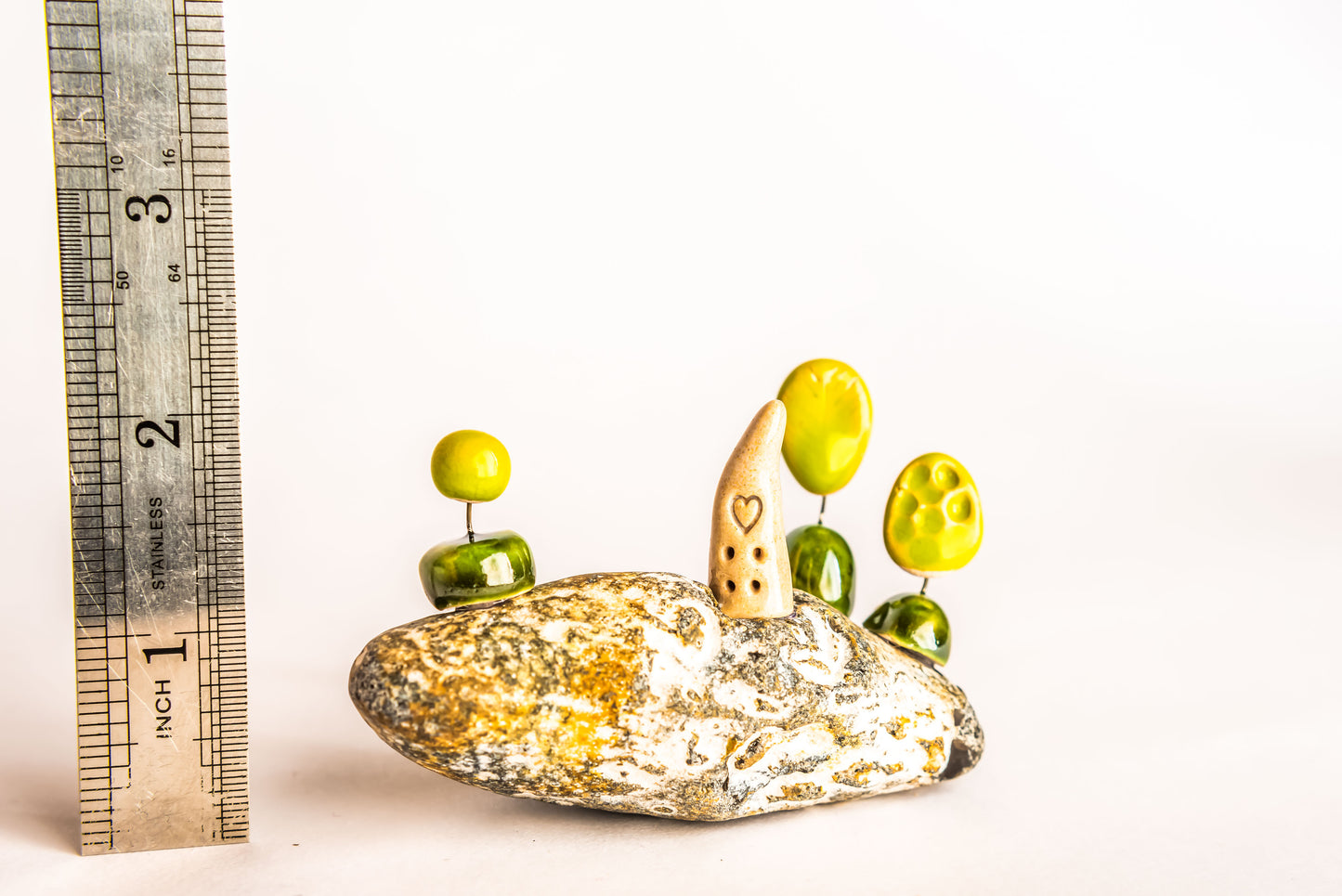 Hand-built fantasy ceramic house on a rock, with three trees