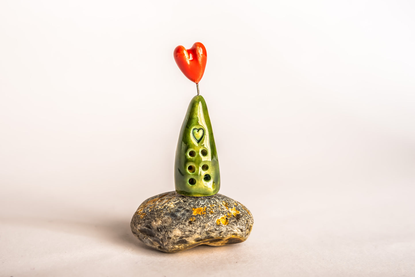 Hand-built green ceramic house on a rock