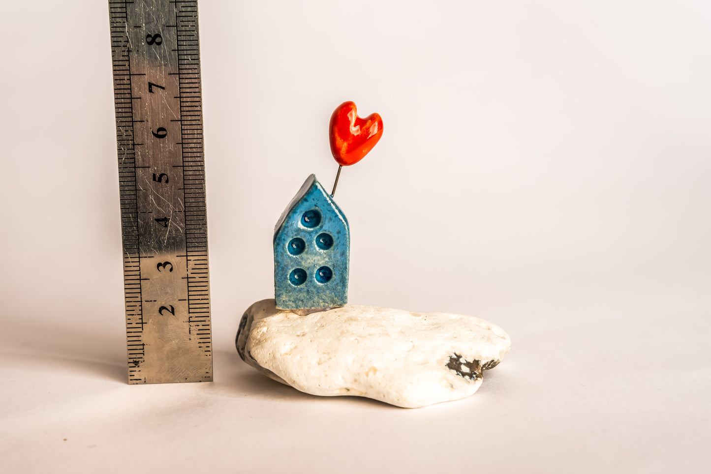 Hand-built blue ceramic house on a rock, with a love heart
