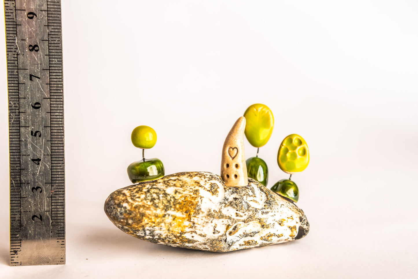 Hand-built fantasy ceramic house on a rock, with three trees
